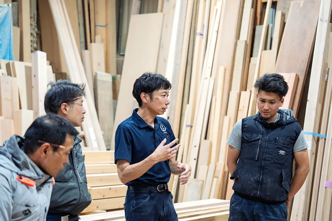 材木置き場で打ち合わせをする岩木建築の職人たち