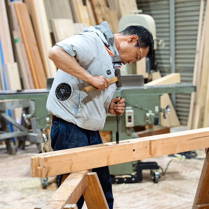 作業場の機械で木材を削る大工